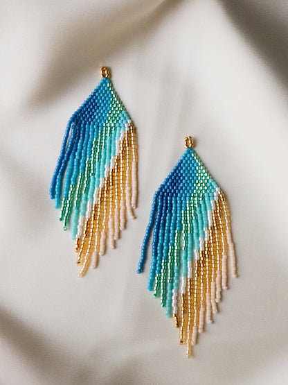 Golden Dawn handmade beaded earrings with cascading strands in blue, green, white, and gold, elegant jewelry inspired by sunrise over golden sands.